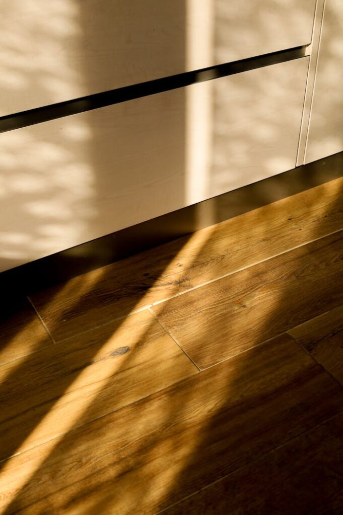 Sunlit shadows cast across a wooden floor, creating a warm and inviting atmosphere indoors.